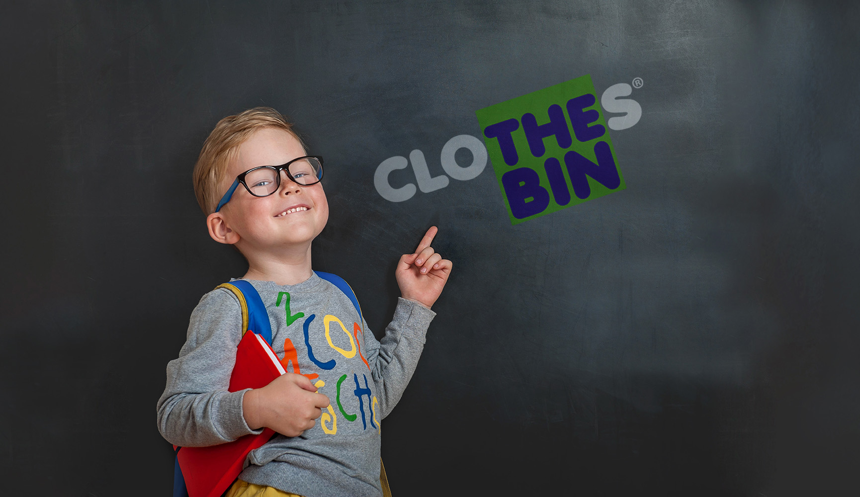 Student pointing at Clothes Bin logo on a chalkboard